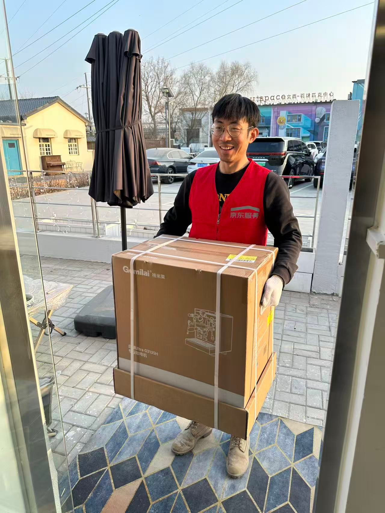 A JD technician carries a large box into a home, smiling. The image captures the friendly, reliable service that defined the campaign.